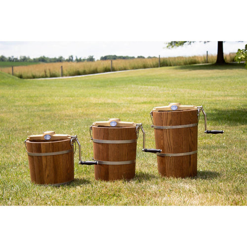 Three handcrafted wooden ice cream freezers with metal bands and crank handles, arranged outdoors on grass, showcasing rugged Amish made construction for Kitchen & Food and Specialty Equipment collections.