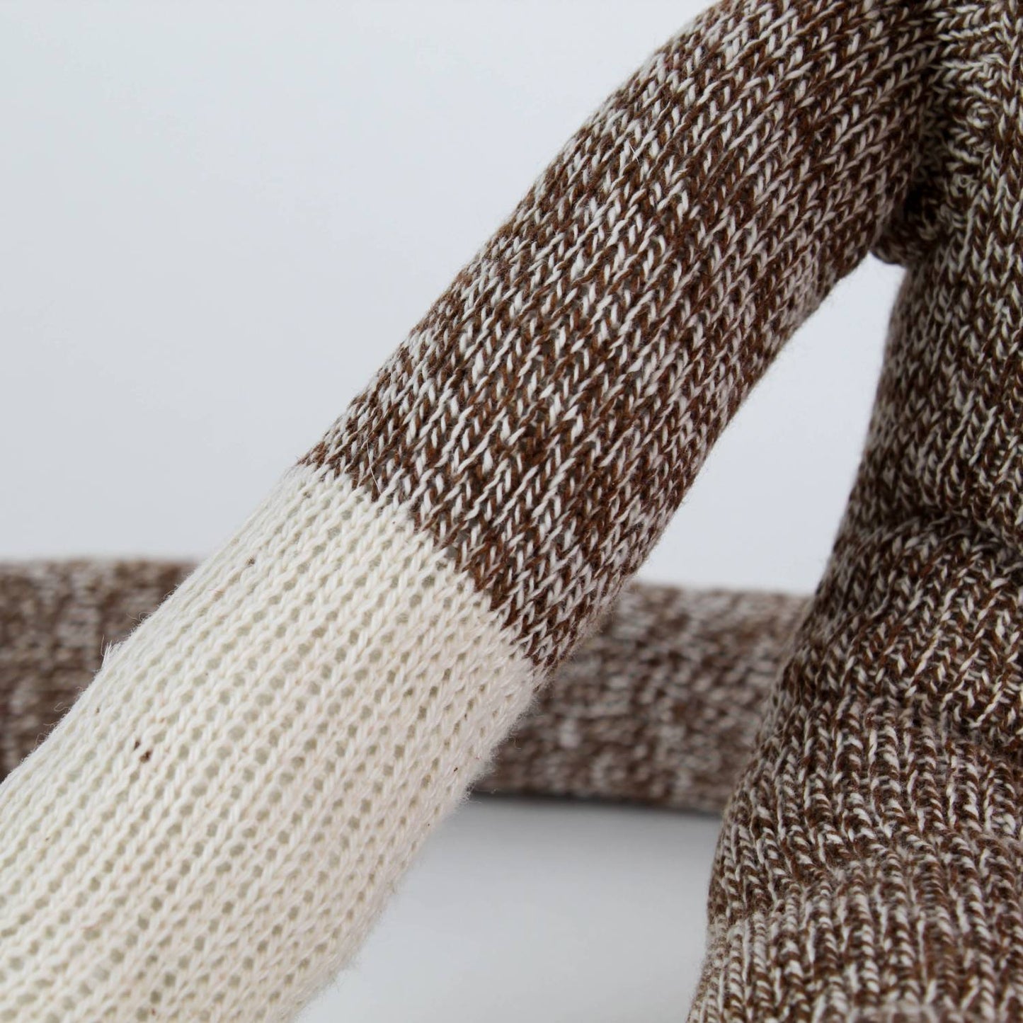 Close-up of a handcrafted arm of a brown and cream knit sock monkey made in USA, featured in Toys, Books & Games, Children's Toys, Indoor Play, and Best Sellers collections.
