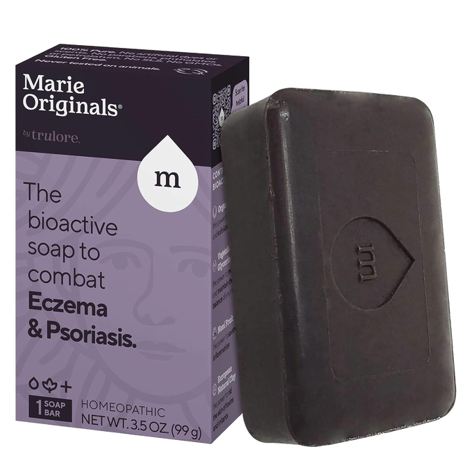 Handcrafted dark brown soap bar embossed with a stylized droplet and letter M, shown next to purple and black packaging highlighting bioactive eczema and psoriasis relief, part of Health & Wellness and Soaps collections.