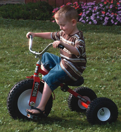 Young boy riding a sturdy red tricycle with heavy-duty air tires on grass, featuring an adjustable seat and steel frame, part of Outdoor Play, Children's Toys, and Best Sellers collections.