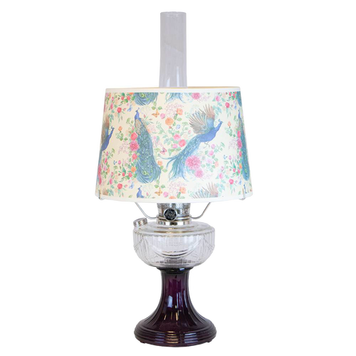 Vintage-style oil lamp with a clear glass bowl over an amethyst pedestal base, featuring a decorative peacock-patterned shade, part of Lamps & Lighting and Best Sellers collections.