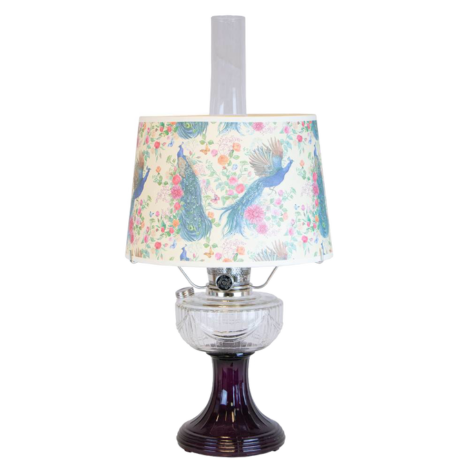 Vintage-style oil lamp with a clear glass bowl over an amethyst pedestal base, featuring a decorative peacock-patterned shade, part of Lamps & Lighting and Best Sellers collections.
