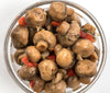 Clear glass bowl filled with marinated whole mushrooms mixed with pieces of red pepper and onions, hand-prepared with natural ingredients, featured in Kitchen & Food and Pantry collections.