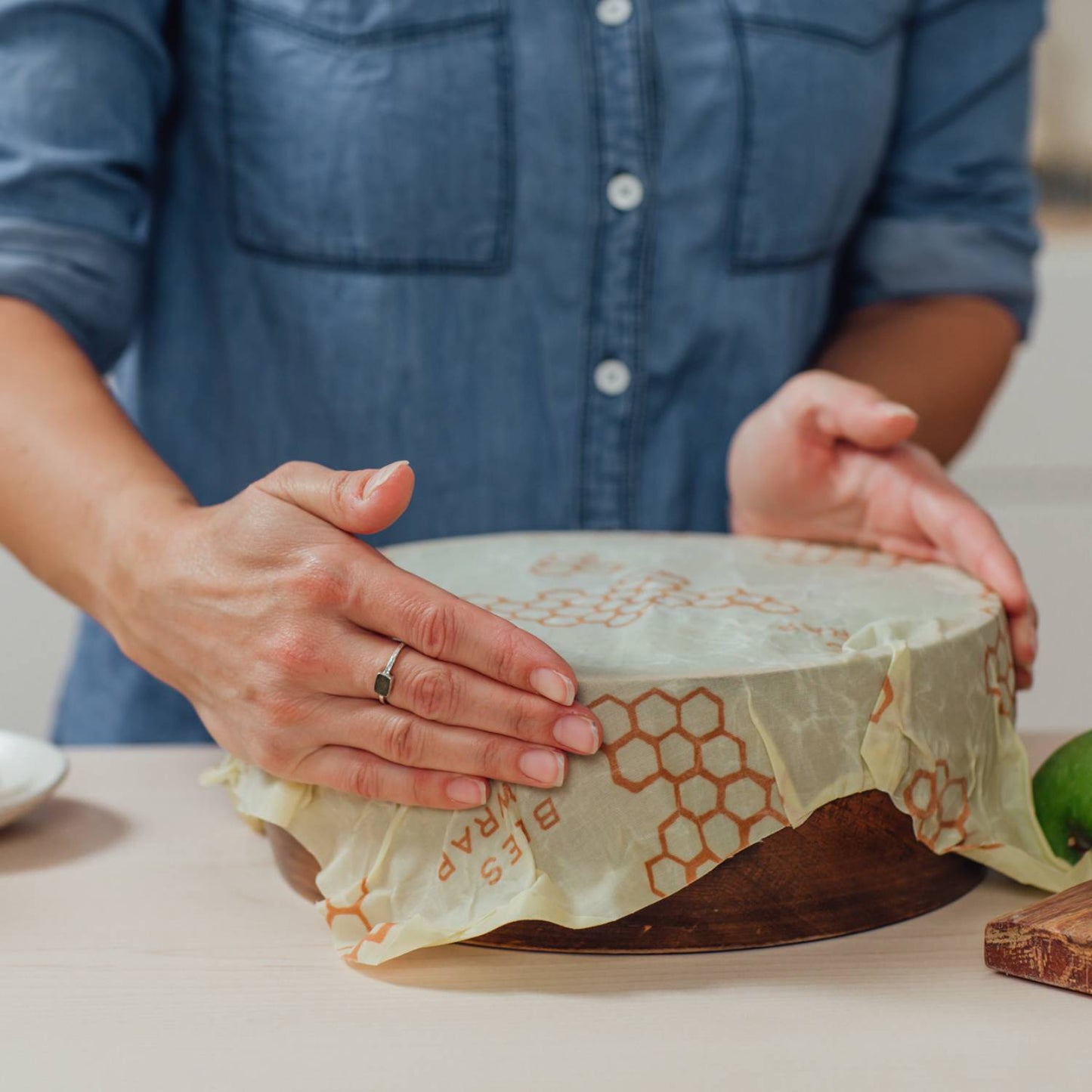 Handmade large beeswax muslin wrap with honeycomb pattern being pressed over a wooden bowl, eco-friendly food storage solution from USA Made and Kitchen & Food collections.