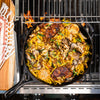 Handcrafted lightweight cast iron skillet cooking a vibrant stir-fry with noodles, mushrooms, herbs, and garlic heads on a grill, suited for Kitchen & Food, Cookware, and USA Made collections.