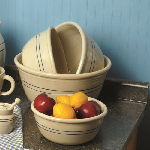 Set of four handcrafted stoneware bowls with blue stripes in varying sizes, arranged on a kitchen countertop with fresh fruit, perfect for baking supplies and holiday hosting collections.