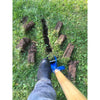 Foot wearing black boot stepping near a narrow trench with clean edges dug in green grass using a blue-handled trenching shovel, displayed in farm and garden tool setting.
