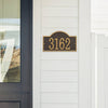 Handcrafted custom address plaque in bronze and gold with arched rectangle design, mounted on white siding near a glass-paneled door, featured in Home & Decor and USA Made collections.