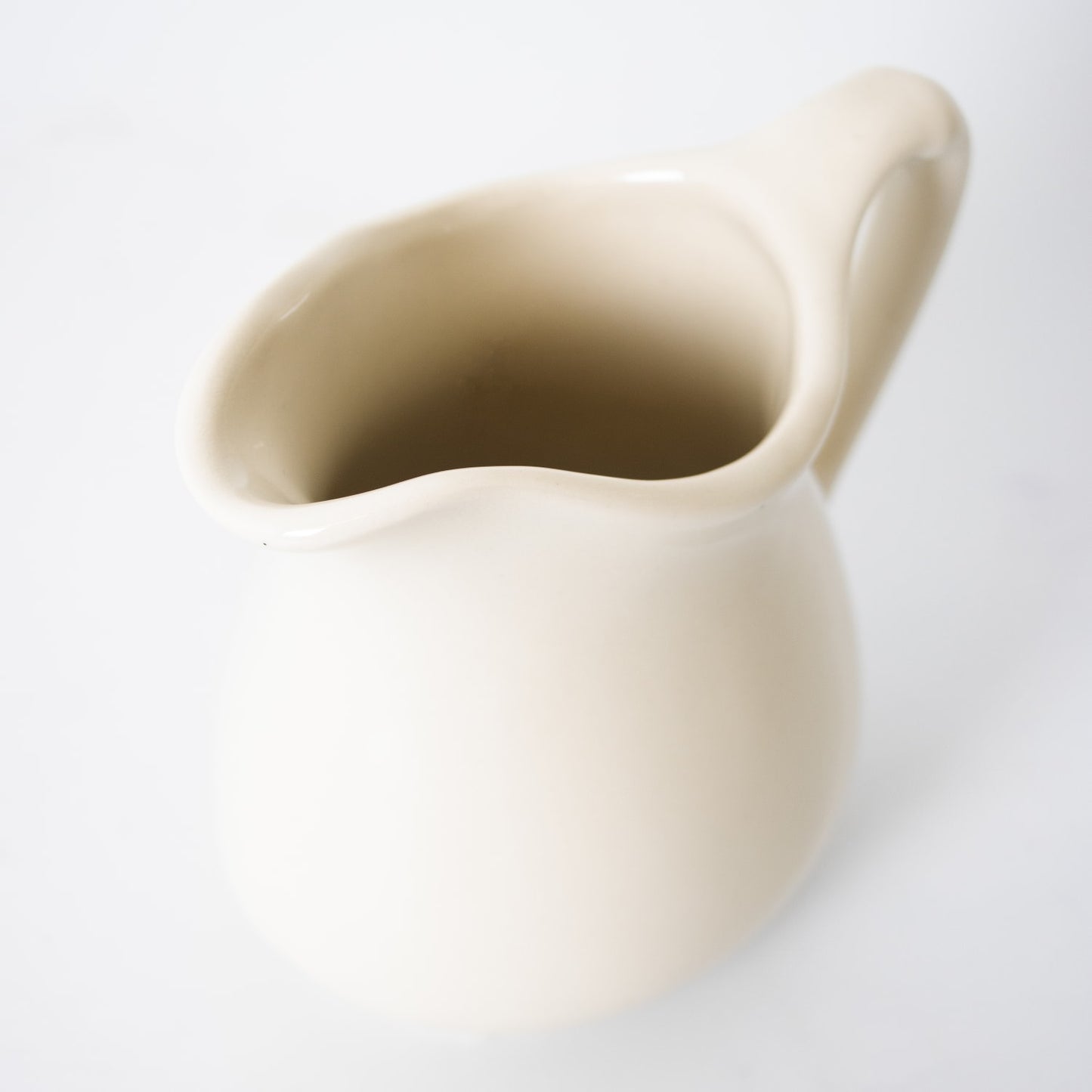 Cream-colored handcrafted stoneware pitcher with smooth finish, designed for serving in Kitchen & Food, Dinnerware, Storage and Serving, USA Made, and Best Sellers collections.