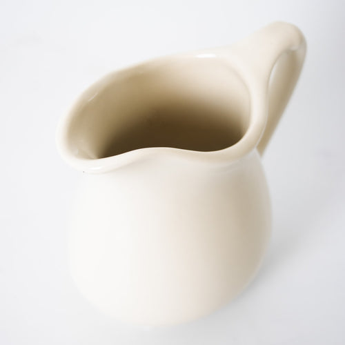Cream-colored handcrafted stoneware pitcher with smooth finish, designed for serving in Kitchen & Food, Dinnerware, Storage and Serving, USA Made, and Best Sellers collections.