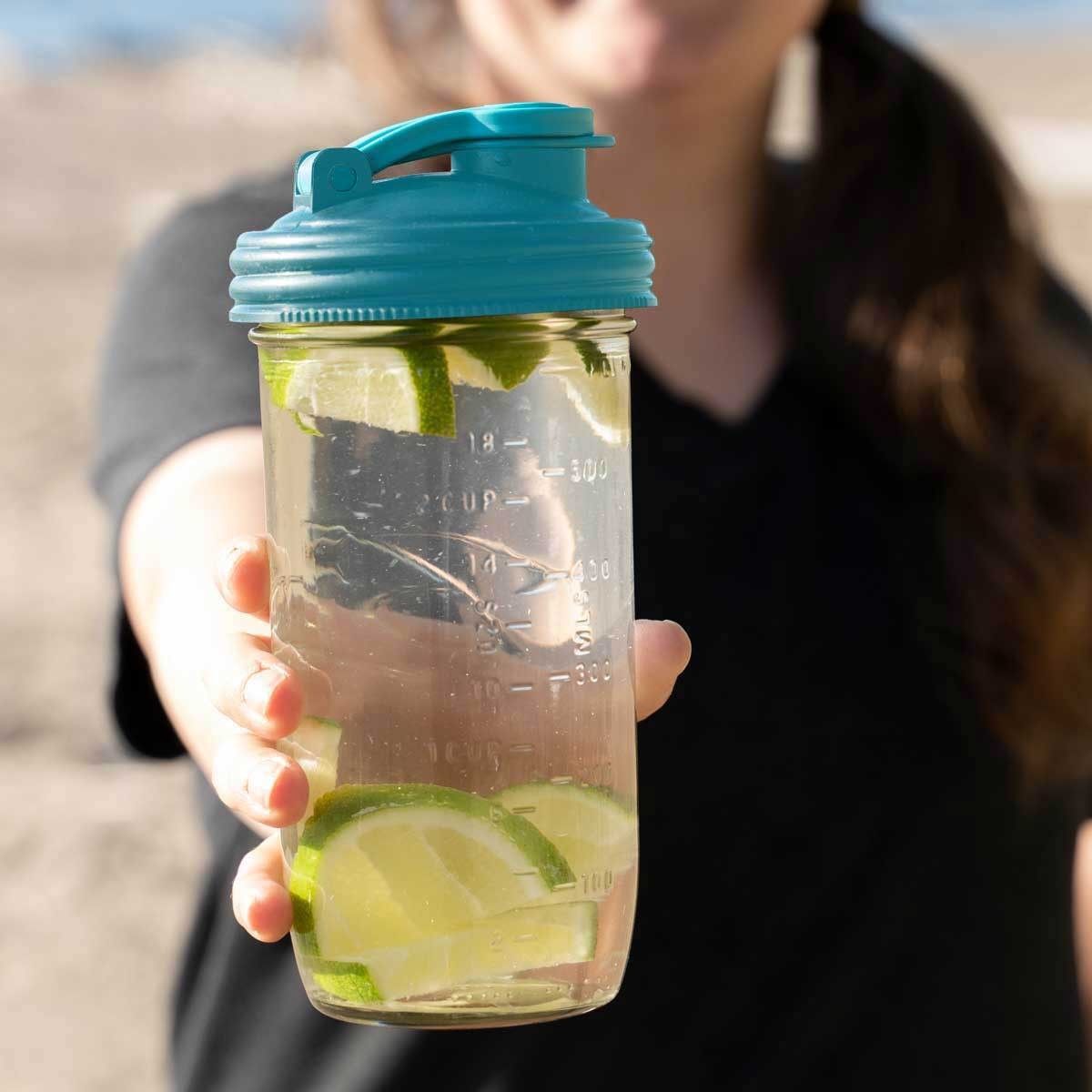 Clear mason jar filled with water and lime slices topped with a bright blue pour lid featuring a flip-top spout and carry loop, ideal for Kitchen Gadgets and USA Made collections.