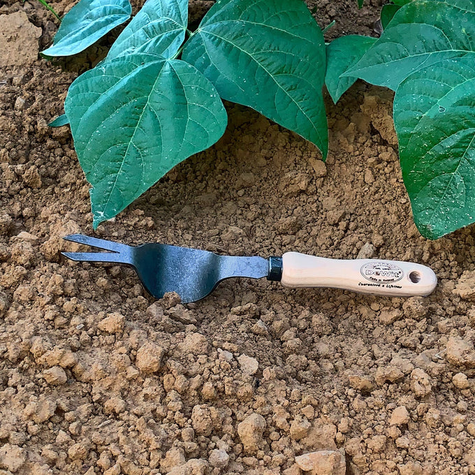 Handcrafted garden weeding tool with a flat arm and dual-pronged metal head, featuring a smooth wooden handle for effective weed removal in farm and garden settings.