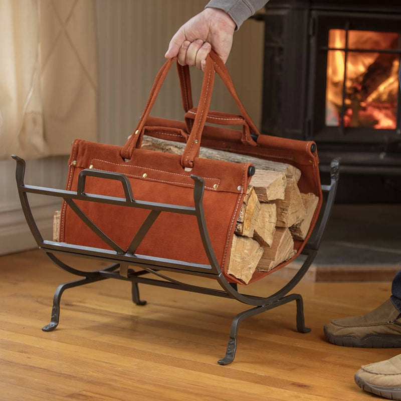 Heavy-steel olde world iron log holder with removable suede leather carrier filled with firewood, set on hardwood floor near a wood-burning stove, suitable for Farm, Garden & Tool and Stoves collections.