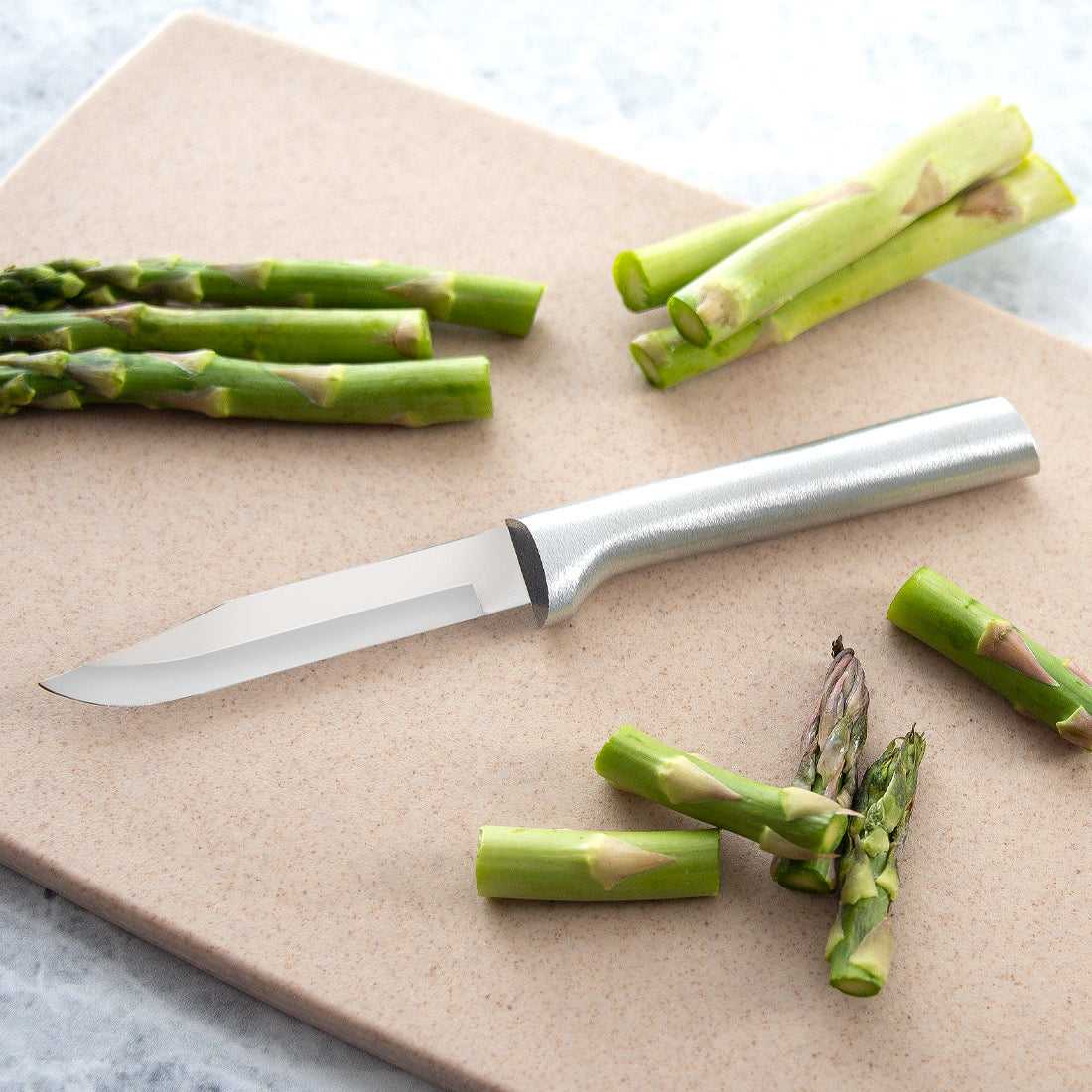 Rada paring knife with a carbon stainless steel blade and cast aluminum handle featuring a non-slip satin finish, displayed on a cutting board with fresh asparagus, ideal for Kitchen & Food, USA Made, and Best Sellers collections.