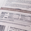 Close-up of nutrition facts and ingredient label on a package of hard red wheat berries, highlighting protein content and usage instructions for bread making and pantry supplies.