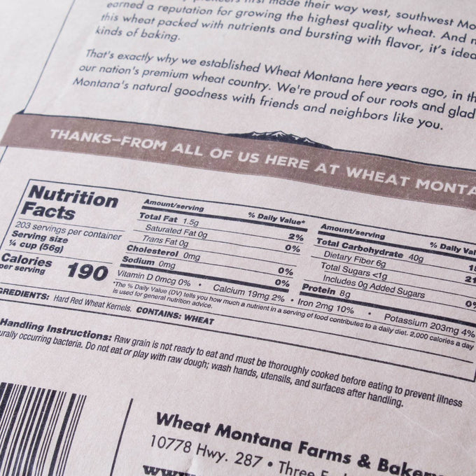 Close-up of nutrition facts and ingredient label on a package of hard red wheat berries, highlighting protein content and usage instructions for bread making and pantry supplies.