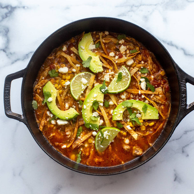 Handcrafted cast iron deep skillet filled with vibrant southwestern stew topped with sliced avocado, lime wedges, corn, tortilla strips, and cheese, featured in Kitchen & Food, Cookware, Cast Iron, USA Made, Best Sellers, and Promo Eligible collections.