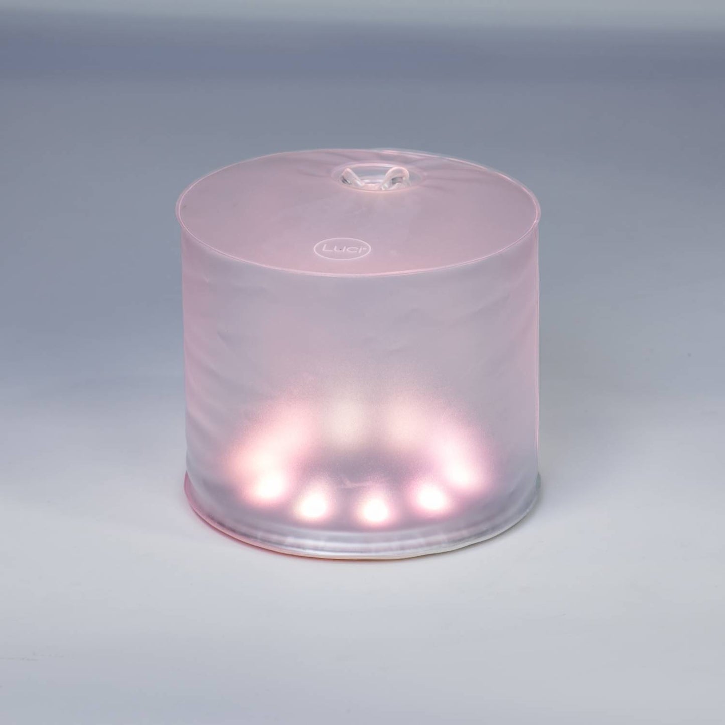 Soft glowing inflatable Luci Color Essence Solar Light emitting a gentle pink hue, designed for eco-friendly use in camping, farm, garden, emergency supplies, and versatile outdoor lighting.