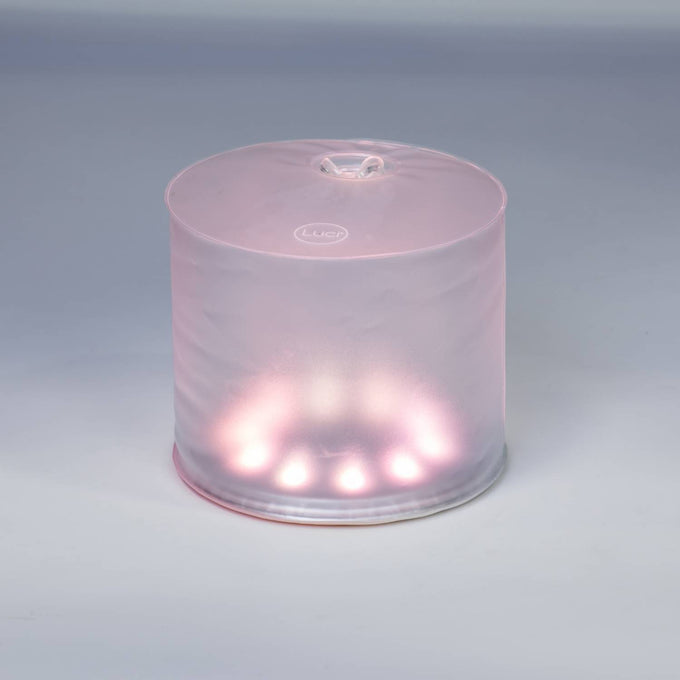 Soft glowing inflatable Luci Color Essence Solar Light emitting a gentle pink hue, designed for eco-friendly use in camping, farm, garden, emergency supplies, and versatile outdoor lighting.