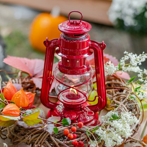 Unique handcrafted red galvanized oil lantern with thermal heat-resistant SUPRAX globe, lit and surrounded by autumn foliage, ideal for Camping, Lamps & Lighting, Emergency Supplies collections.