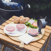 Black metal single hamburger press with adjustable thickness lever, shown with raw beef patties on wax paper, fresh burger buns, lettuce, tomato, and onion on wooden table, ideal for Kitchen & Food, Specialty Equipment, Butchering Supplies, Best Sellers, and Promo Eligible collections.