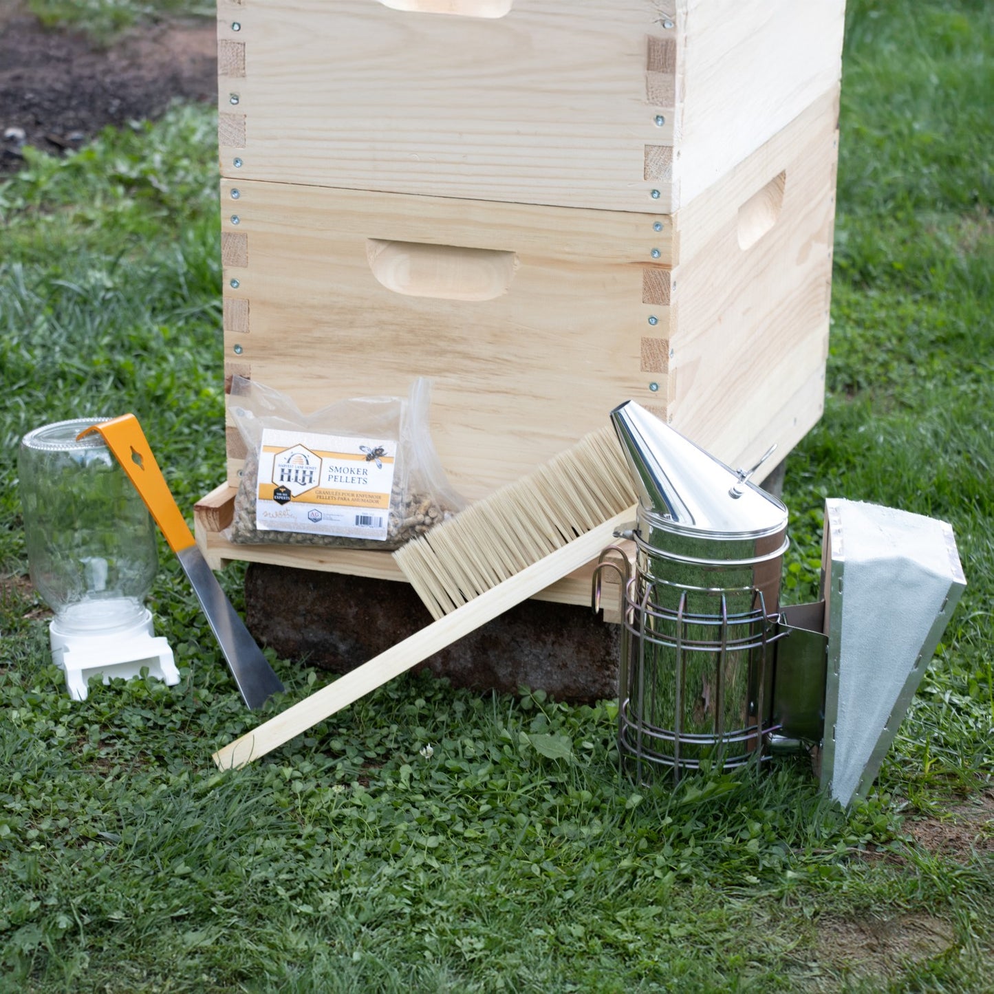 Handcrafted natural wood 8-frame beehive kit with smoker, bee brush, hive tool, and smoker pellets arranged on grass, ideal for Farm, Garden & Tool and Beekeeping Supplies collections.