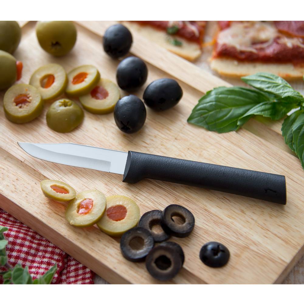 Paring knife with a smooth black handle and a sharp stainless steel blade, ideal for detailed food prep tasks like slicing olives on a wooden cutting board, USA made.