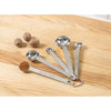 Set of five linked stainless steel measuring spoons with engraved measurements, containing ground spice in one spoon, displayed on a wooden surface with whole nutmegs; featured in Kitchen & Food, Food Prep, Measuring, Best Sellers, and Promo Eligible collections.
