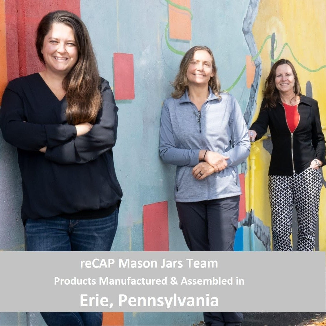 Three smiling women standing in front of a colorful mural wall representing the reCAP Mason Jars team from Erie, Pennsylvania, featured in USA Made, Kitchen Gadgets, and Best Sellers collections.