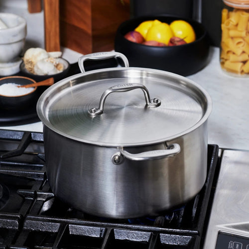 Handcrafted fully clad stainless steel stock pot with lid resting on a gas stove burner, showcasing durable design for Kitchen & Food, Cookware, Pots and Pans collections.