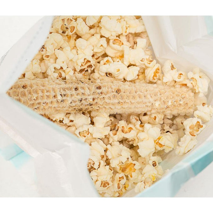 Popped popcorn surrounding a fully popped empty cob inside a microwave bag, highlighting a wholesome snack made in USA, ideal for Kitchen & Food, Snacks, Popcorn, and Best Sellers collections.