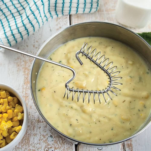 Unique coil whisk with angled stainless steel design resting in a bowl of creamy soup, ideal for thorough mixing, made in USA, featured in Kitchen & Food and Cooking and Baking Helpers collections.