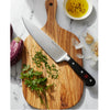 Sharp chef's knife with high carbon stainless steel blade and triple-riveted full tang handle resting on a wooden cutting board with chopped herbs, garlic, and olive oil, ideal for Kitchen Knives, Food Prep, and Best Sellers collections.