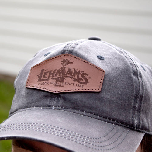 Close-up of a handcrafted adjustable hat in washed cotton with a weathered vintage style and a light brown leather patch featuring a windmill design, ideal for Health & Wellness, Clothing and Accessories, Best Sellers, and Promo Eligible collections.
