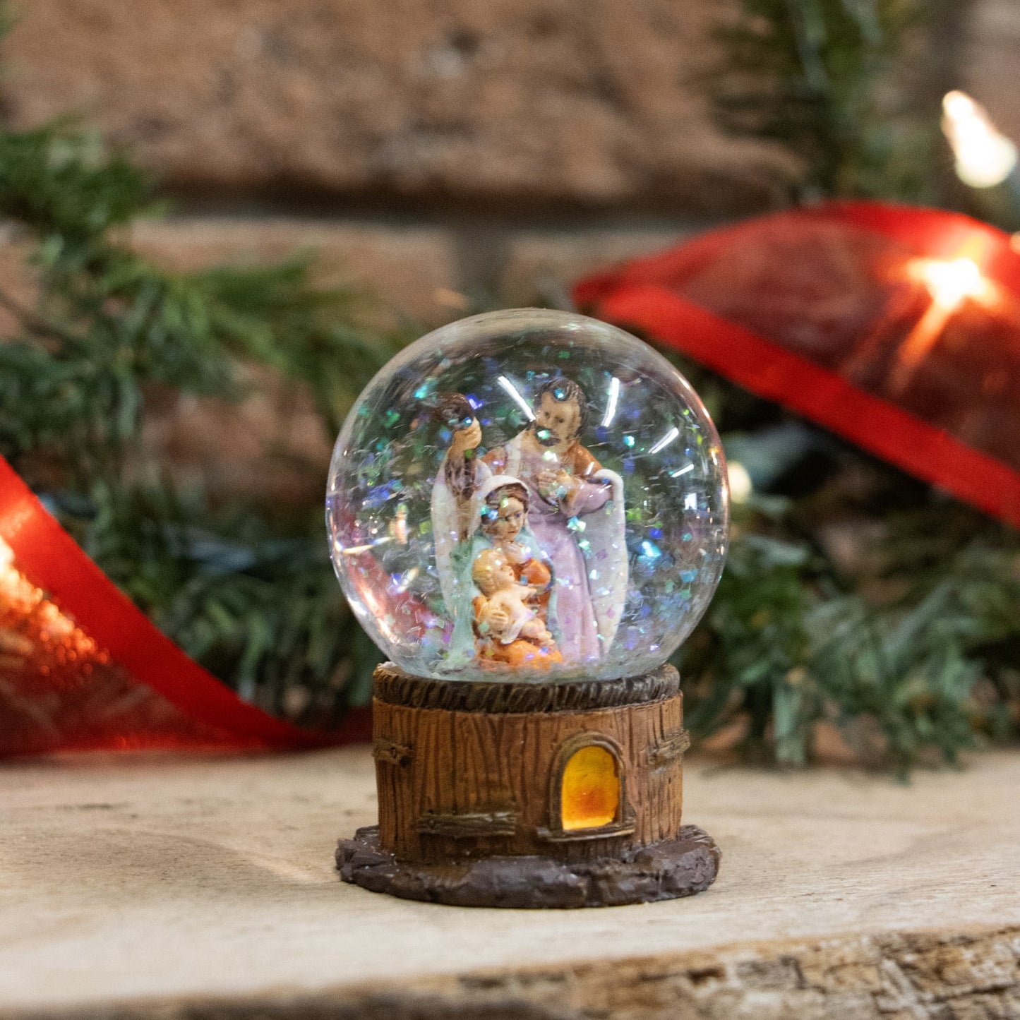 Handcrafted miniature snow globe featuring a glitter-filled glass dome with hand-painted Holy Family figurines inside, set on a rustic wood-style base, perfect for Home & Decor and Holiday Decor collections.