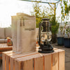 Padded beige nylon carrying case with reinforced structure and zipper closure, next to a black vintage-style lantern, ideal for camping, emergency supplies, and outdoor lighting needs.
