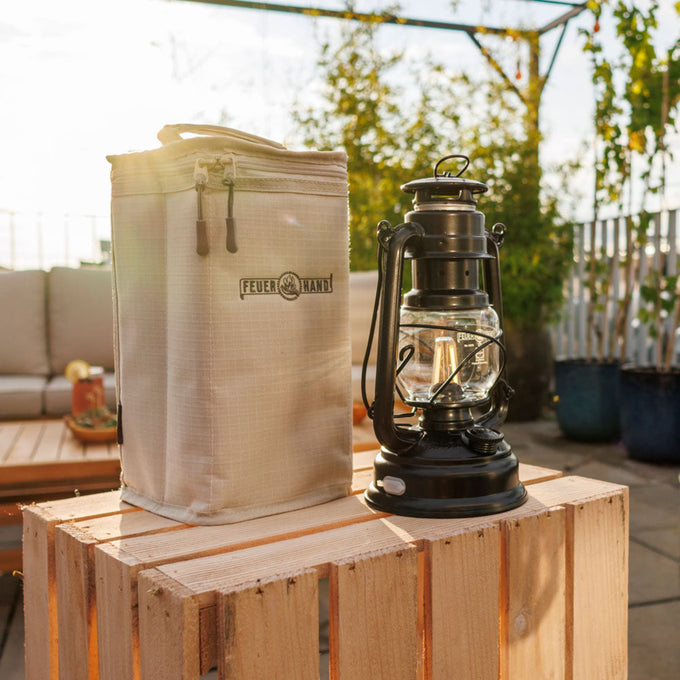 Padded beige nylon carrying case with reinforced structure and zipper closure, next to a black vintage-style lantern, ideal for camping, emergency supplies, and outdoor lighting needs.