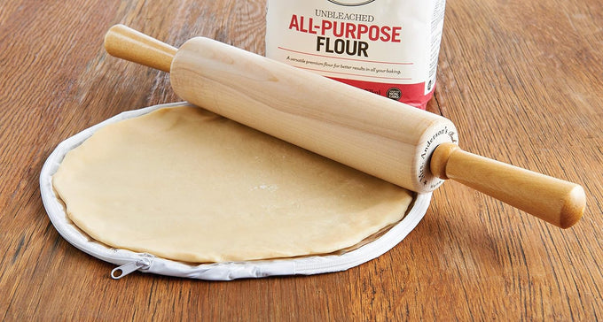 Wooden rolling pin resting on flattened dough inside a clear zippered plastic bag with flour bag in background, ideal for Kitchen & Food, Cookware, Baking Supplies, Best Sellers, and Promo Eligible collections.