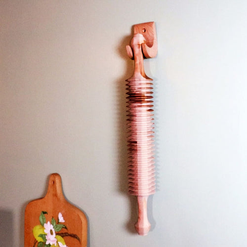 Handcrafted unfinished cherry wood noodle cutter with carved handle, mounted on wall, showcasing unique Amish-made craftsmanship for Kitchen & Food, Food Prep, and Best Sellers collections.