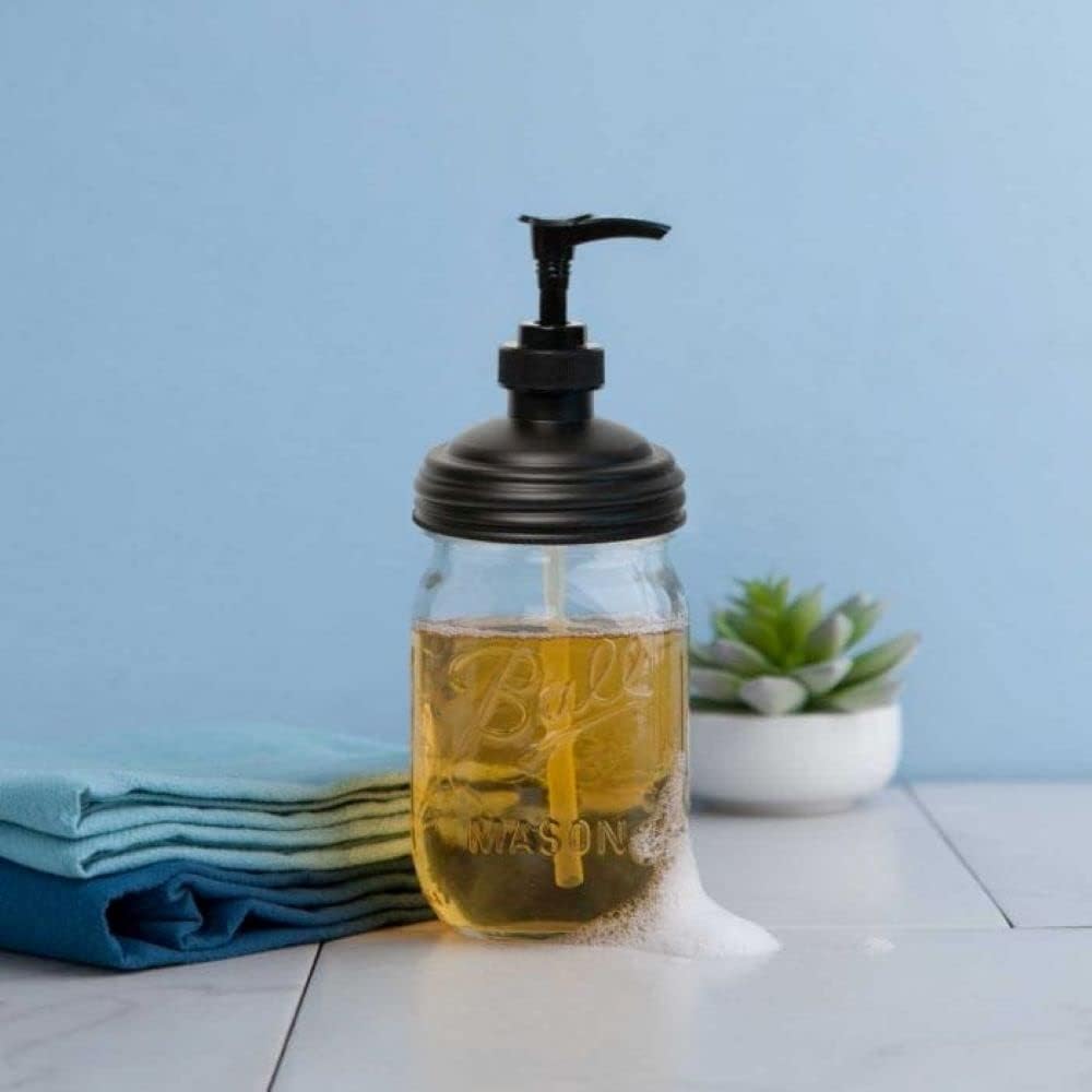 Clear glass mason jar filled with golden soap and topped with a black pump lid, sitting on a white surface with folded blue cloths and a small succulent nearby, highlighting eco-friendly, USA made Household Helpers and Home & Decor collections.