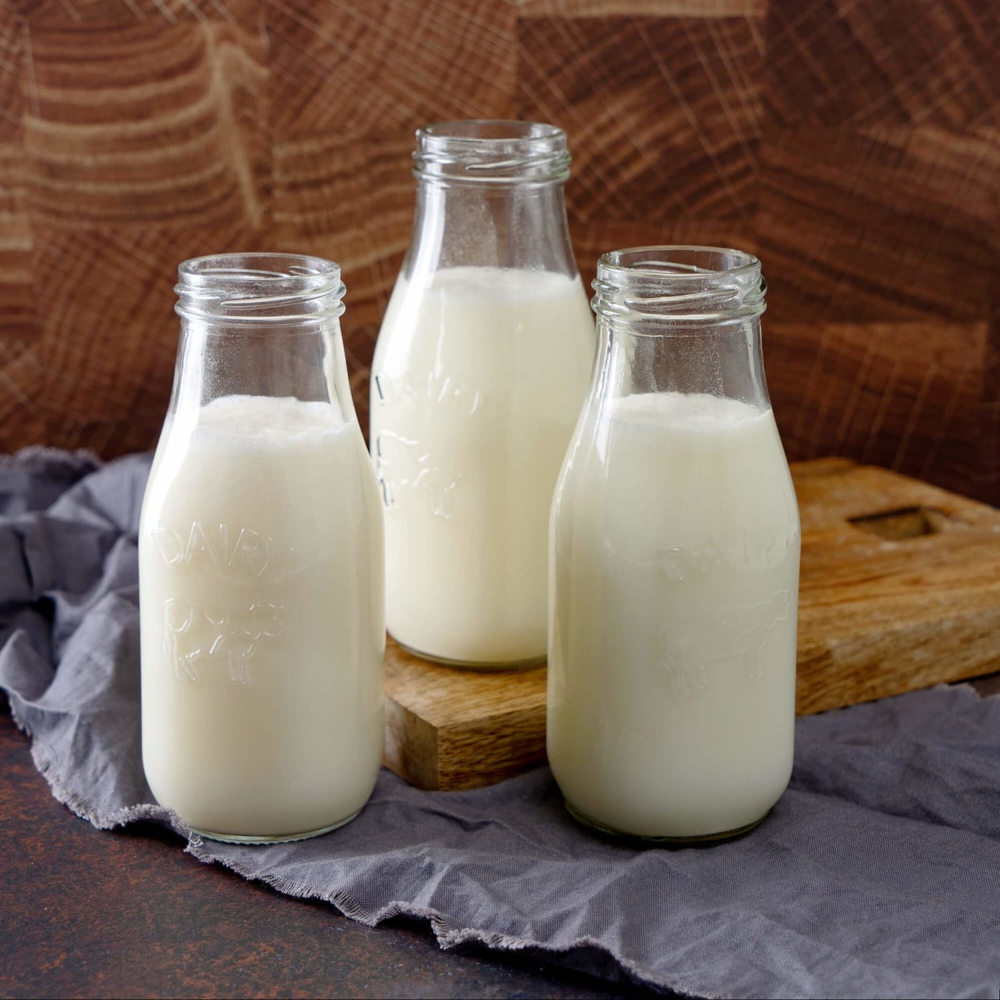 Three clear glass bottles filled with white liquid placed on a wooden surface with a folded grey cloth, evoking emergency supplies and USA Made collections like Farm, Garden & Tool and Best Sellers.