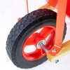 Close-up of a rugged rubber tire with deep tread on a child's wheelbarrow featuring sturdy wood handles and a bright red metal frame, part of Toys, Books & Games and Lawn Games collections.