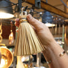 Handcrafted miniature straw broom with a metal loop for hanging, shown held by hand in a kitchen setting, part of USA Made Kitchen Gadgets and Cooking Helpers collections.