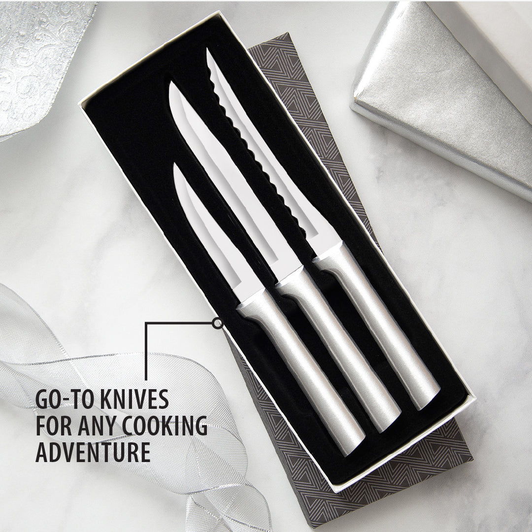 Three-piece set of sharp knives with sleek silver handles in a black gift box, including heavy-duty paring, utility, and serrated tomato slicer knives, handcrafted in the USA.