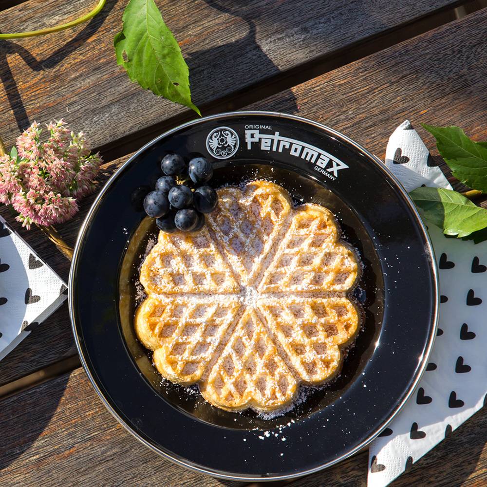 Black enamel plate with Petromax logo holding a heart-shaped waffle dusted with powdered sugar and fresh dark grapes, designed for camping, kitchen, Farm, Garden & Tool, Dinnerware, and Best Sellers collections.
