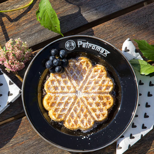 Black enamel plate with Petromax logo holding a heart-shaped waffle dusted with powdered sugar and fresh dark grapes, designed for camping, kitchen, Farm, Garden & Tool, Dinnerware, and Best Sellers collections.