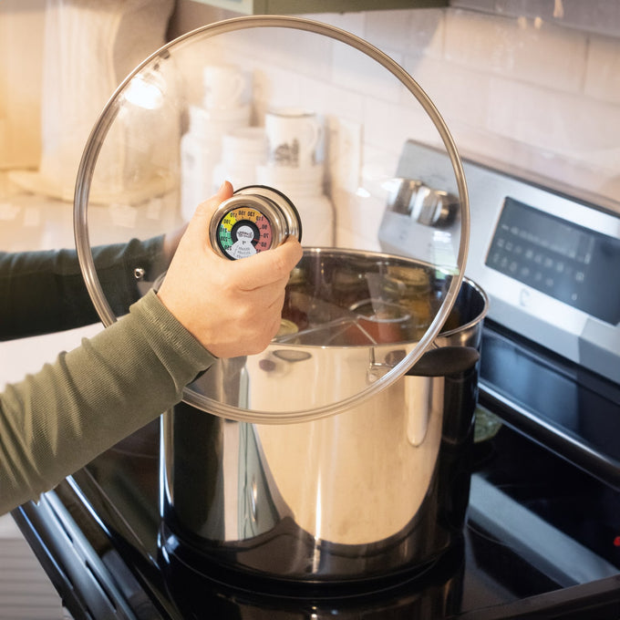 Handcrafted stainless steel water bath canner with clear glass lid featuring built-in temperature gauge, shown on stovetop for Kitchen & Food, Food Preservation, and Canning collections.