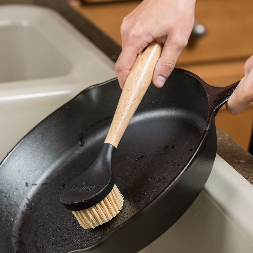 Handheld scrub brush with sturdy nylon bristles and ergonomic rubberwood handle, designed for cleaning cast iron cookware, featured in Kitchen & Food, Cookware, Cast Iron, Best Sellers, and Promo Eligible collections.