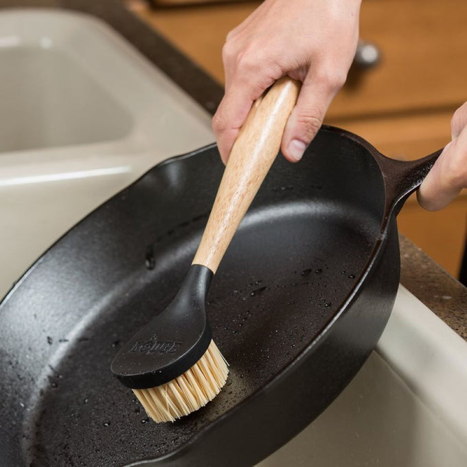 Handheld scrub brush with sturdy nylon bristles and ergonomic rubberwood handle, designed for cleaning cast iron cookware, featured in Kitchen & Food, Cookware, Cast Iron, Best Sellers, and Promo Eligible collections.