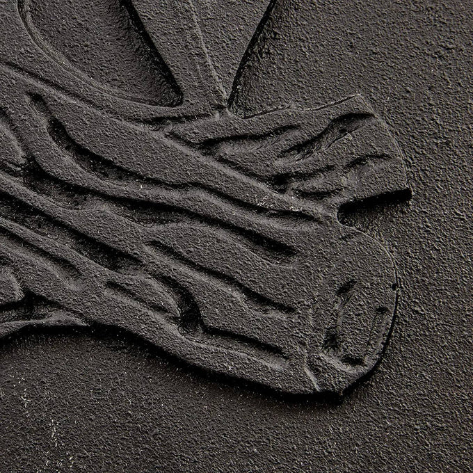 Close-up of a handcrafted cast iron stove door panel featuring detailed embossing of stacked logs, designed for use in stoves, hearth accessories, and heatstoves collections.